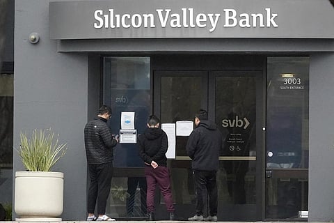 People look at signs posted outside of an entrance to Silicon Valley Bank in Santa Clara. (Photo | AP)