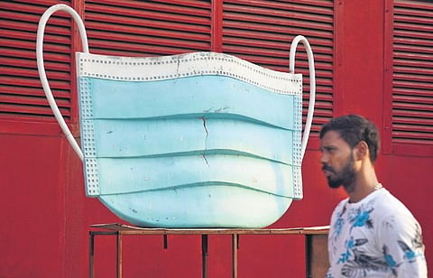 Amid daily count of Covid-19 cases on the rise, a man walks past the model of a mask, at Nandhanam metro station, Chennai | Ashwin Prasath