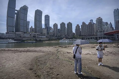 FILE - Students carrying umbrellas stand on the dry riverbed of the Jialing Rivera, a tributary of the Yangtze, in southwestern China's Chongqing Municipality, Aug. 19, 2022. (Photo | AP)