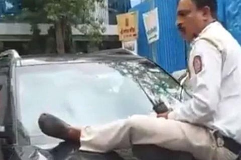 On February 2023: A screengrab from a video showing a traffic police constable being dragged on the bonnet of a car for nearly 1.5 km in Maharashtra.