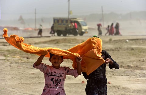 Children use a cloth to shield themselves from the scorching heat on a hot summer day, at Sangam in Prayagraj. (Photo | PTI)