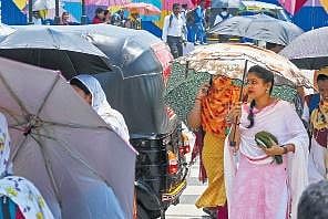 People crossing a street holding umbrellas to protect themselves from the  scorching heat at Master Canteen in Bhubaneswar, on Tuesday | DEBADATTA MALLICK