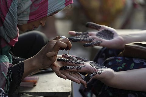 A beautician paints hands of customers with traditional henna in preparation for the upcoming Eid al-Fitr celebrations, in Karachi, Pakistan, Thursday, April 20, 2023. (Photo | AP)