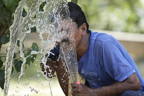 FILE - A person sprays water on his face from an irrigation pipe to beat the intense heat wave in Lucknow in the the Indian state of Uttar Pradesh, April 19, 2023.  (Photo | AP)
