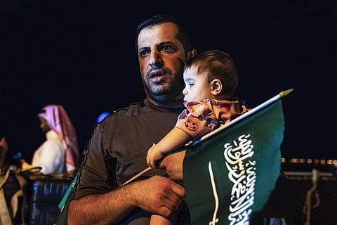 FILE: An evacuee holds a child and a Saudi flag as they arrive at Jeddah Port on Monday, April 24, 2023, after being evacuated from Sudan to escape the conflict. (Photo | AP)