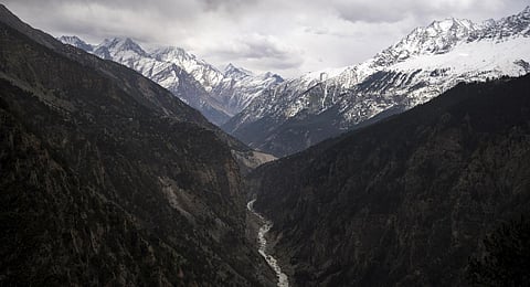 Sutlej River flows in the valley below the tall snowy peaks in Himachal Pradesh.
