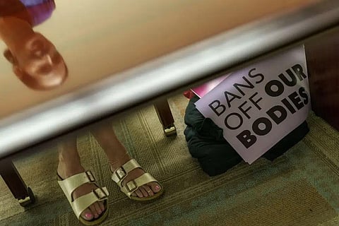File - Planned Parenthood advocacy programs manager, Allison Terracio, is reflected in a table as signs sit in the clinic's office in Columbia, S.C., Friday, May 27, 2022. (Photo | AP)