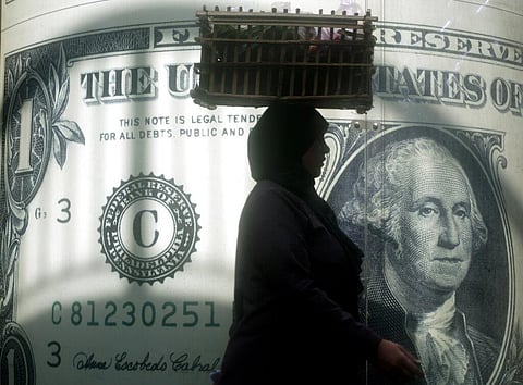 Representational Image: An Egyptian vendor walks past a poster showing a U.S. dollar outside an exchange office in Cairo, Nov. 9, 2016. (File Photo|AP)
