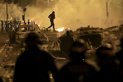 A demonstrator runs on the third night of protests sparked by the fatal police shooting of a 17-year-old driver in the Paris suburb of Nanterre. (Photo | AP)