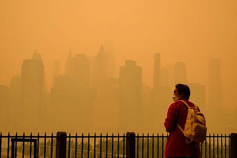 n orange-tinged smog caused by Canada's wildfires shrouded New York causing residents to don face masks. (Photo | AFP)