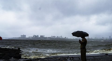 A police personnel stand guard at the coastline amid monsoon rains as high tidal waves crash at the shore, in Mumbai, Wednesday, July 19, 2023.(Photo | PTI)
