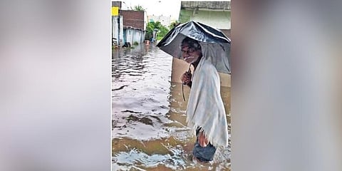 An elderly man wades through knee-deep water that inundated several colonies in Adilabad on Saturday 