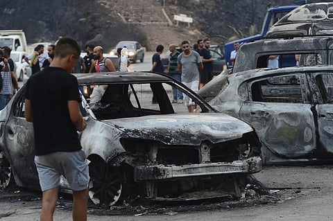 People inspect burnt vehicles after raging wildfires in Bouira, 100 km from Algiers, Algeria, July 24, 2023.  (Photo | AP)