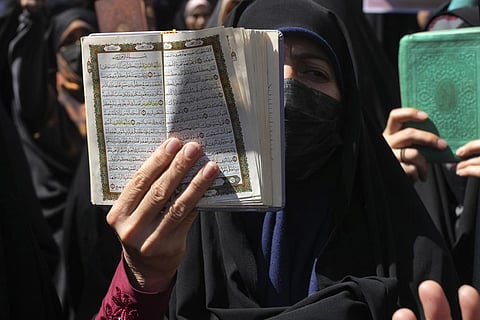 A demonstrator holds up a copy of the Quran, Islam's holy book, during a protest of the burning of a Quran in Sweden, in front of the Swedish Embassy in Tehran, Iran. (Photo | AP)