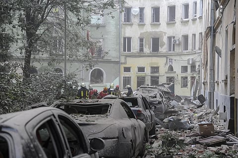 Emergency service workers gather outside damaged buildings as search for victims continues following a Russian missile attack in Lviv. (Photo | AP)