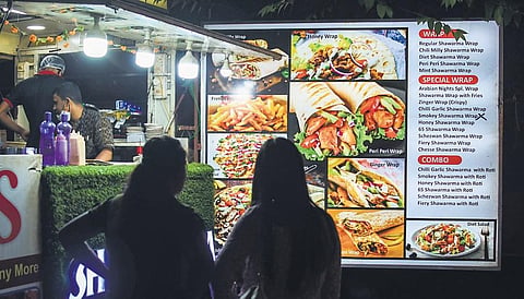 Customers look at the menu chart of a roadside food stall in Bhubaneswar.