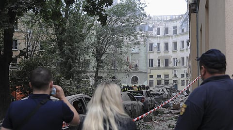 People watch as emergency service workers continue to search for victims after a Russian missile attack in Lviv, Ukraine. 