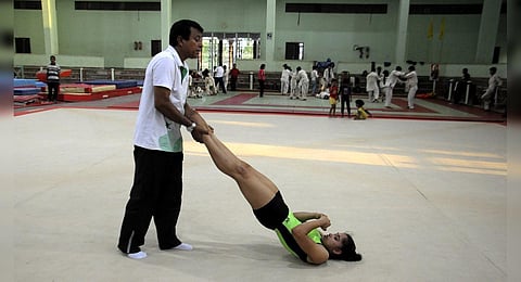FILE - Indian gymnast Dipa Karmakar (R) stretches with her coach Bisbeshwar Nandi during a practice session in Agartala. (Photo | AFP)