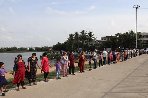 School children and member of various  NGOs form a human chain at Kapra Lake in Sainikpuri on Sunday. (Photo | Sri Loganathan Velmurugan)