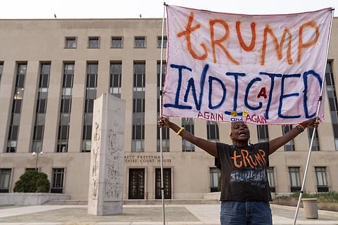 A protestor holds a banner outside federal court in Washington after Donald Trump was charged by the US Justice Department for trying to overturn the 2020 presidential election. (Photo | AP)