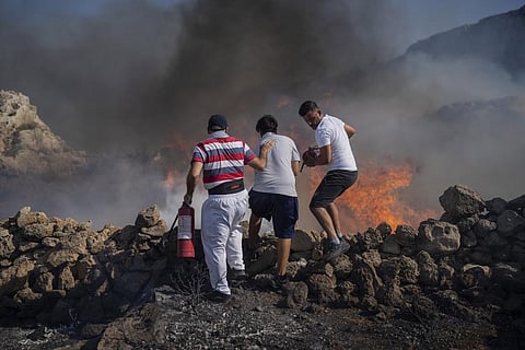 Local residents try to extinguish a fire, near the seaside resort of Lindos, on the Aegean Sea island of Rhodes. (Photo | AP)
