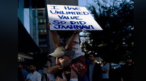 A girl sits atop her father's shoulders while holding a sign for Jaahnavi Kandula, during a protest in Seattle, after the footage of a cop joking about her death came to light.