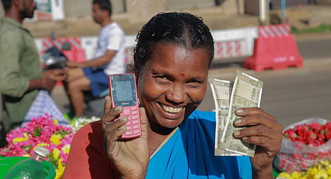 Rani, a widow who sells flowers, poses after receiving Rs. 1000 under  Kalaignar Scheme for Right of Women. (Photo | PTI)