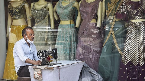 A tailor waits for customers outside a shop at Kamala Nagar market.