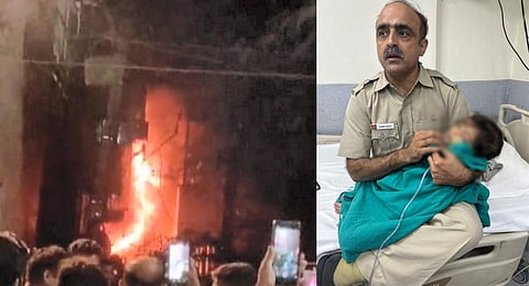 A police official holds a rescued baby at a hospital after a fire broke out in a building in Delhi's Mukherjee Nagar, on Sept 27, 2023. (PTI)