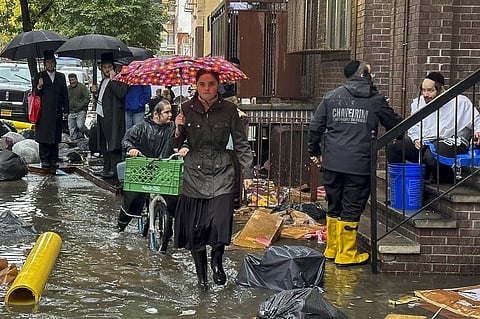 Pedestrians walk along a flooded sidewalk on September 29, 2023, in the Brooklyn borough of New York. (Photo | AP)