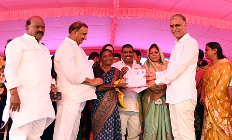Finance Minister Harish Rao hands over ownership documents to the beneficiaries of double bedroom houses at Kollur near Hyderabad on Saturday. (Photo | Express)
