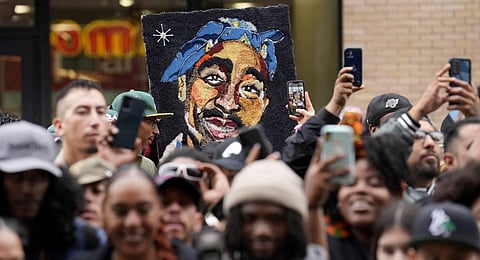 An image of the late rapper and actor Tupac Shakur appears among fans during a ceremony honoring Shakur. 