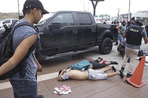 Men lie face down on the ground, detained by police outside TC Television, after a producer told police that they were part of a group who broke onto their set during a live broadcast. (Photo | AP)