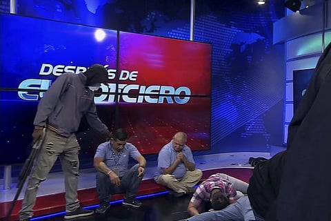 This screen grab of live video from the TC Television network shows a masked, armed person standing over journalists during a live broadcast, in Guayaquil, Ecuador. (Photo | AP)