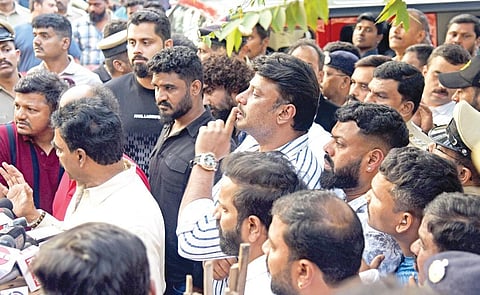 Actor Darshan gestures to the crowd outside the Subramanyanagar police  station in Bengaluru on Friday. Actor Abhishek Ambareesh looks on | vinod kumar t