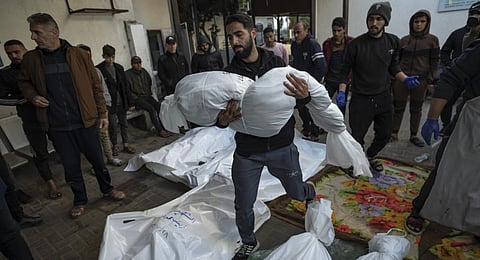 A Palestinian man carries the body of his relative killed in the Israeli bombardment of the Gaza Strip, outside a morgue in Rafah. (Photo | AP)