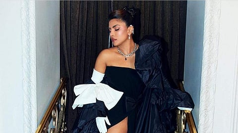 Priyanka Chopra Jonas wore a Valentino black cady strapless dress with black bow detail and leather gloves along with a black faille cape with a white bow.