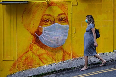 
A pregnant woman walks past a street mural in Hong Kong on March 23, 2020. With the coronavirus pandemic moving quickly, pregnant women are facing a changing health care system. Anthony Wallace/AFP via Getty Images
