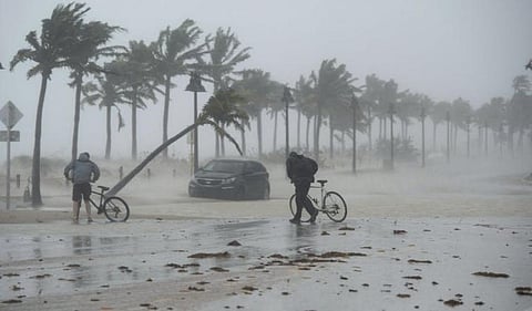 Two people walk their bicycles along a flooded street on the waterfront of Fort Lauderdale, Fla., as Hurricane Irma passes through on September 10, 2017. Photo: THE CANADIAN PRESS
