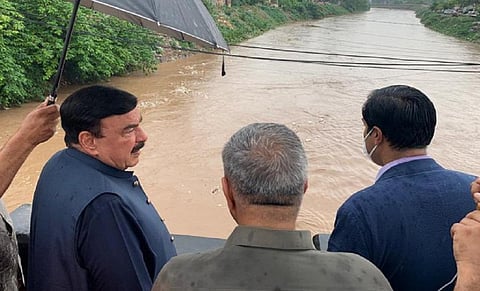 Pakistan's Interior Minister, Sheikh Rashid Ahmed looks at floodwaters from the Gawalmandi bridge to assess the flood situation in Rawalpindi. Photo: @ShkhRasheed / Twitter 