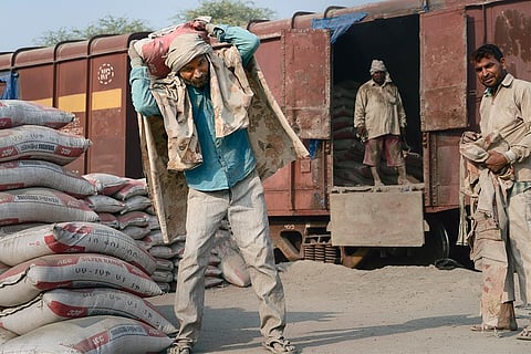 मथुरा में मालगाड़ी से सीमेंट की बोरियां उतारते मजदूर; फोटो: आईस्टॉक
