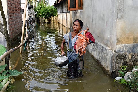 असम में बाढ़ से जद्दोजहद करती स्थानीय महिला; फोटो: आईस्टॉक