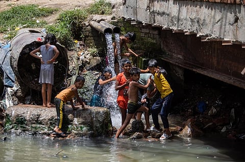  Children find some respite from the summer heat in Delhi, as they cool off under water flowing from an unfinished pipeline into a drain. 

