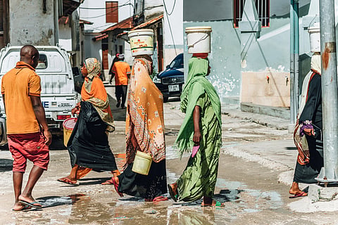 Zanzibar women carrying home water after collecting it in buckets 