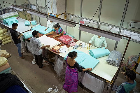 Workers folding and wrapping textiles in plastic on the floor of a Mumbai dyeing and printing mill.