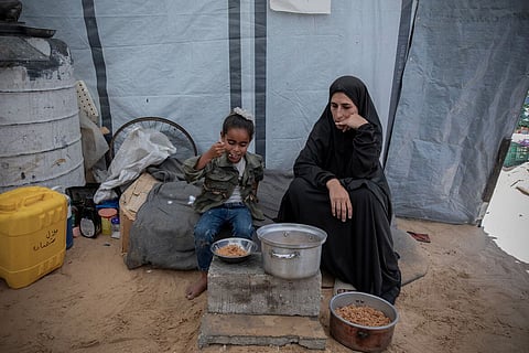A woman watches on as a child eats at a camp in Gaza.