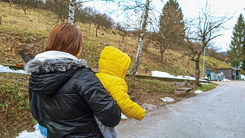 A mother carries her child after arriving in Bosnia and Herzegovina, seeking safety and stability for her family after a long journey. 
