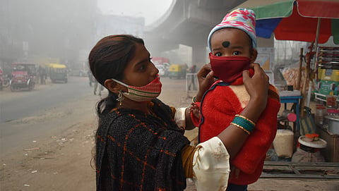 A woman adjust her baby's protective mask on a winter morning in Kolkata, India
