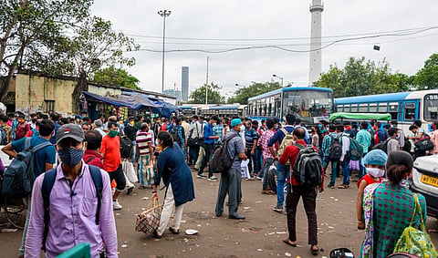 Migrant workers with masks wait at a bus stand during the COVID-19 unlock period in Kolkata in October 2020. Photo: iStock