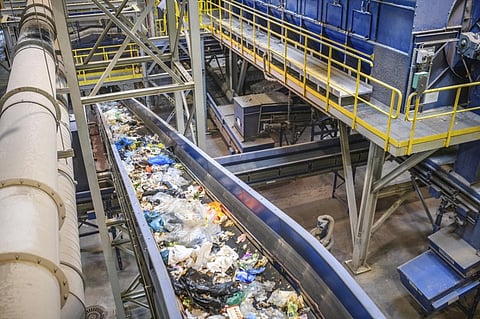 Pieces of recyclable garbage on conveyor belt inside waste management facility. Photo: iStock